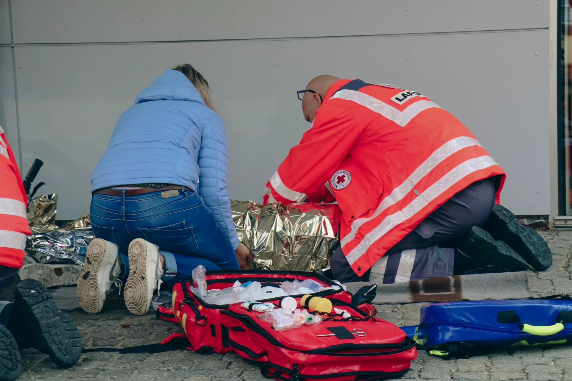 Ersthelfer haben einen Patienten in eine Rettungsdecke gewickelt und versorgen ihn.