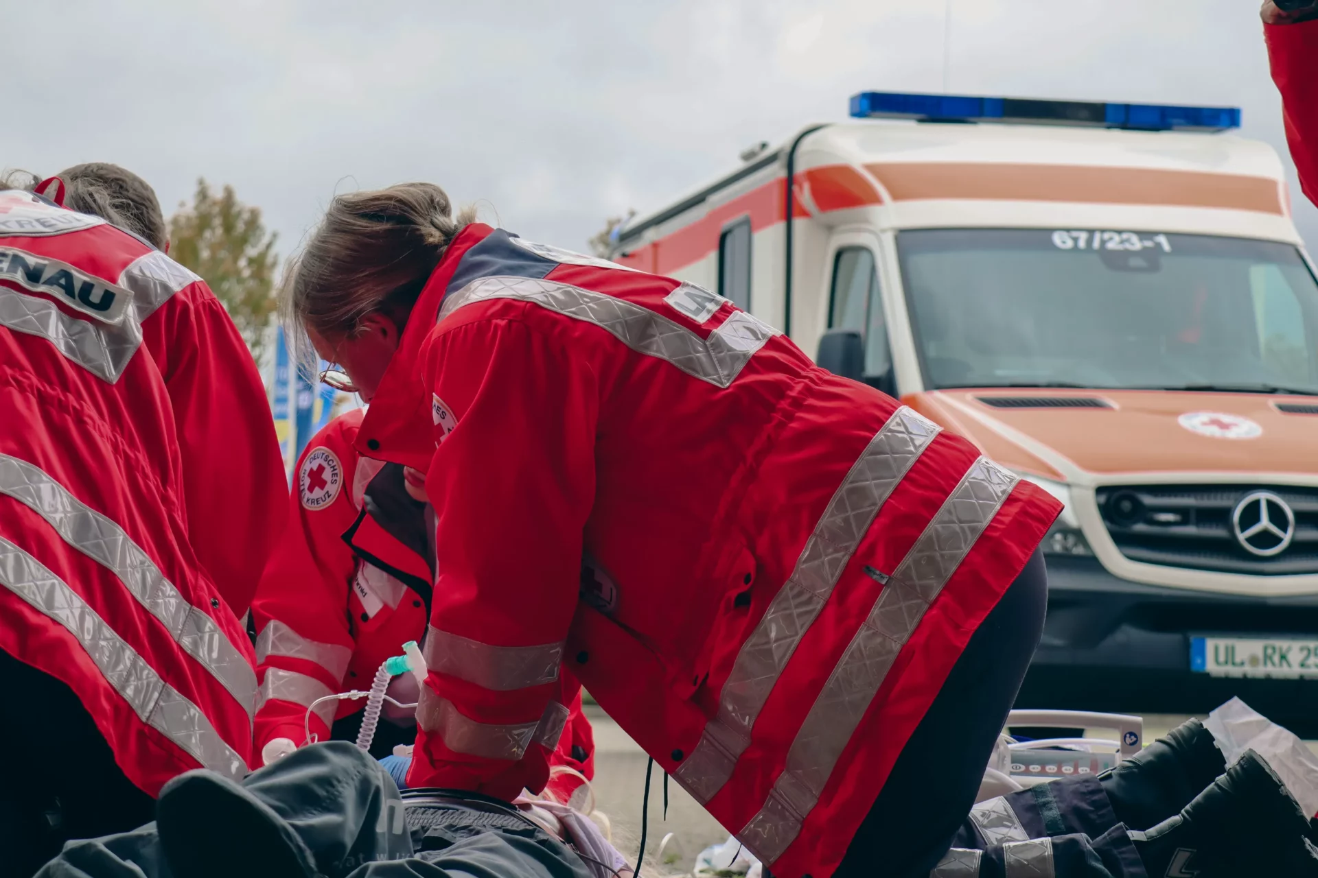 Rettungssanitäterin bei der Herzdruckmassage an einem Patienten unter freiem Himmel